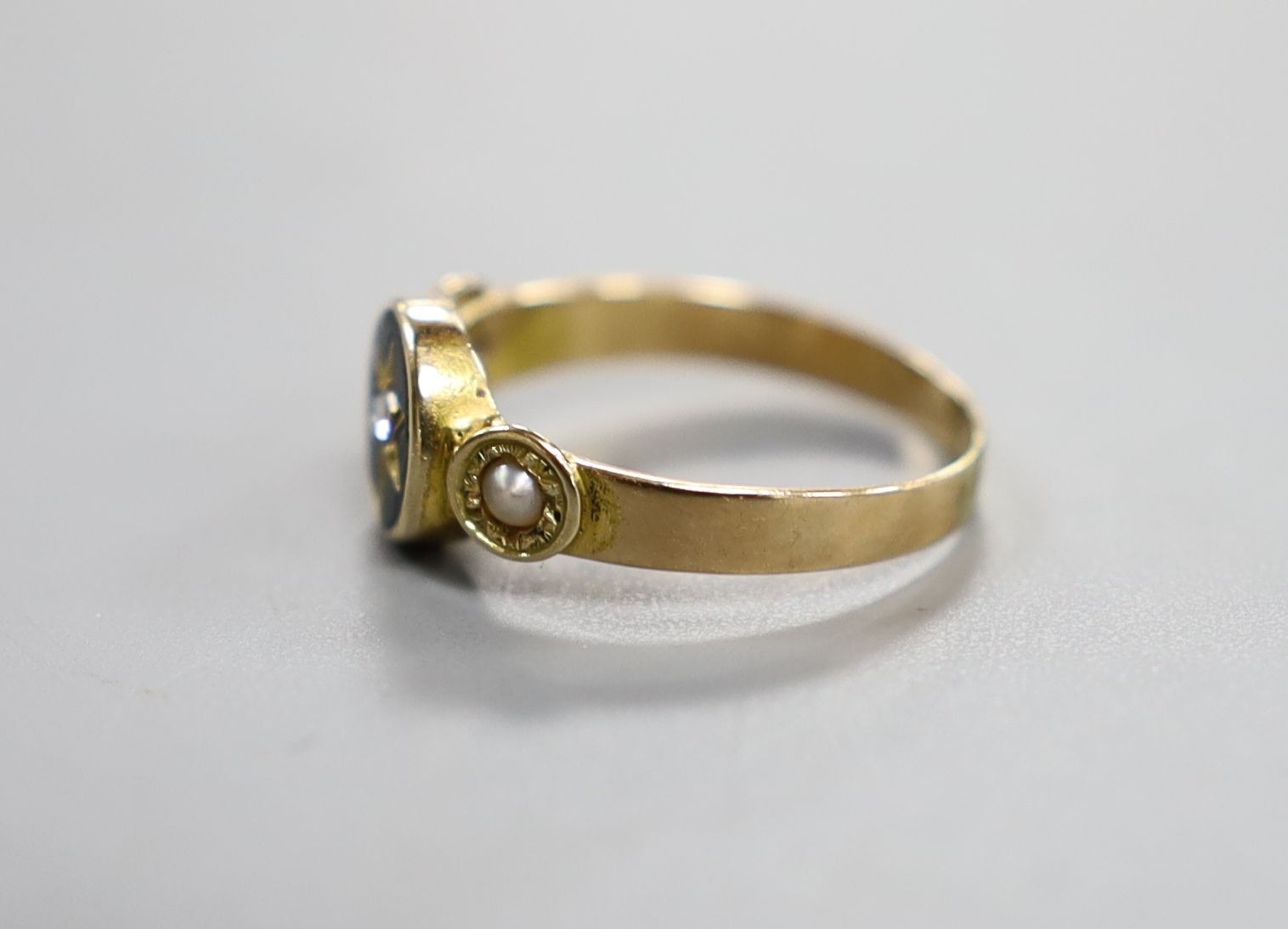 A Victorian yellow metal black enamel, seed pearl and diamond set mourning ring, size O/P, gross weight 2.3 grams.